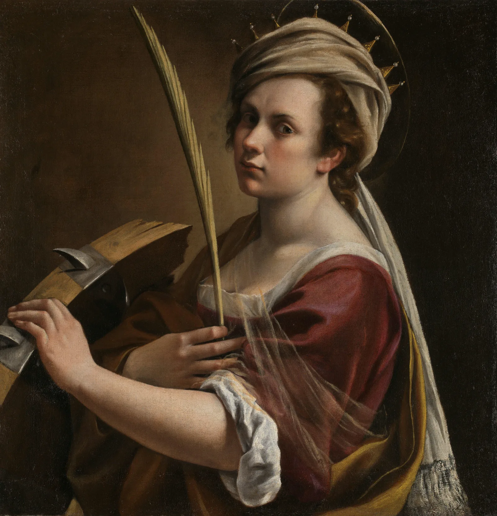 A half-length woman in a yellow shawl turns toward the viewer, one hand resting on the top of a broken spiked wheel and the other holding a palm frond; a faint halo sits above her head.