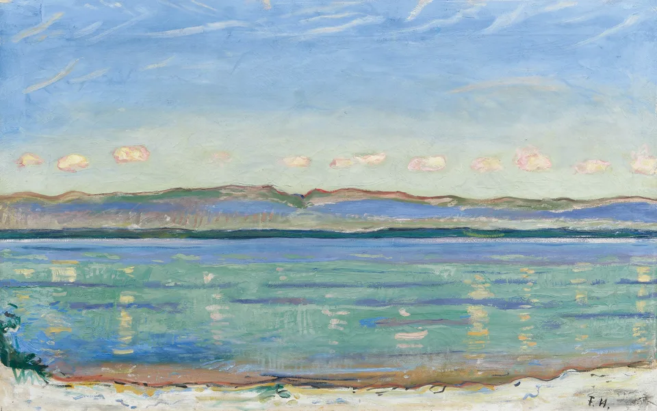 A wide view across Lake Geneva toward the low, flat chain of the Jura mountains, built in horizontal bands of shoreline, water reflecting clouds, and distant hills.