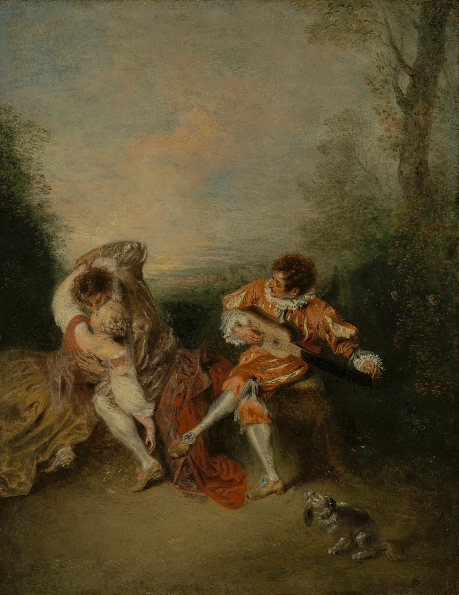 An actor dressed as Mezzetin sits on a stone outcrop in a garden at the end of the day, tuning a guitar beside an embracing couple, while a small dog watches.